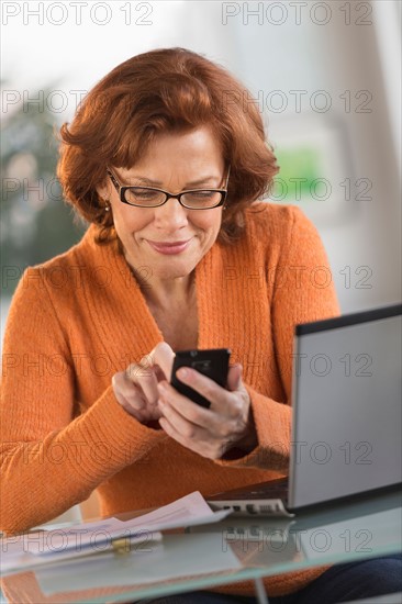 Senior woman working on laptop and text messaging.
