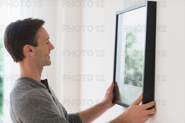 Man hanging picture on wall.