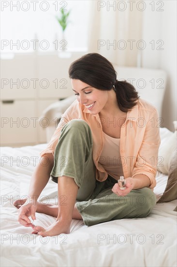 Woman doing pedicure in bedroom.