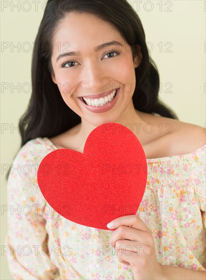 Young woman holding red paper heart.