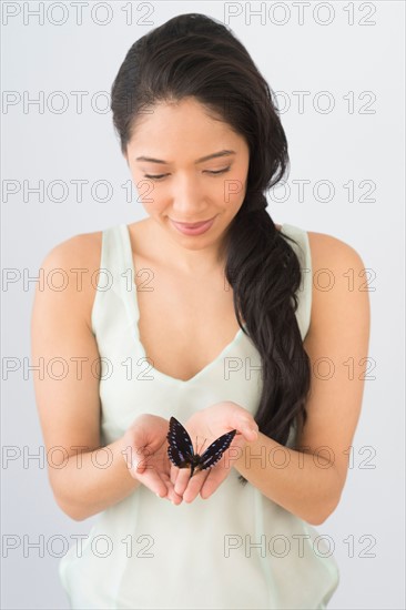Young woman holding butterfly.