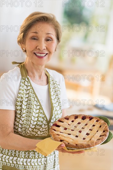 Senior woman holding freshly baked cake.