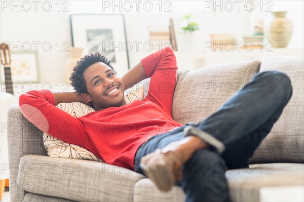 Man lying on sofa and smiling.