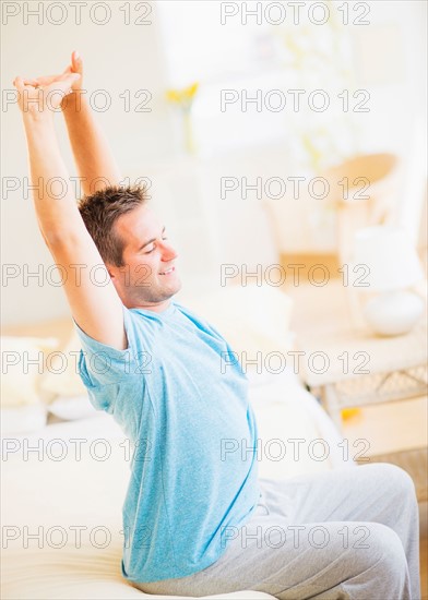 Man sitting on bed and stretching