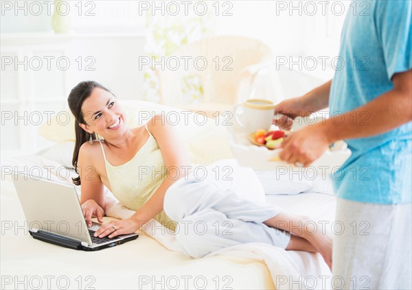 Man serving breakfast to woman in bed