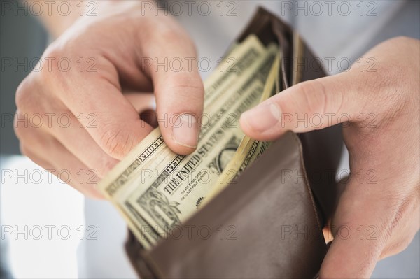 Young man holding wallet and counting money.