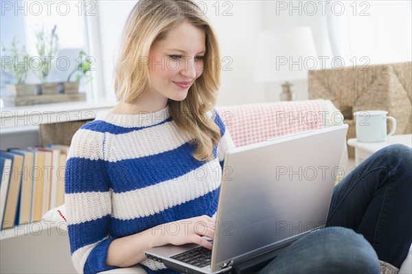 Woman sitting on sofa and using laptop.
Photo : Jamie Grill