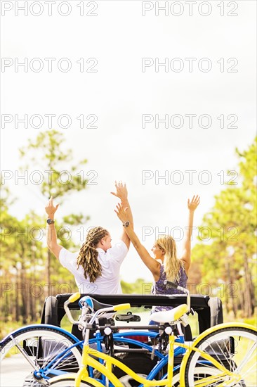 Couple rising hands in car