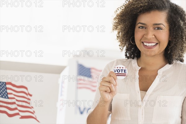 Young woman holding voting badge and smiling.