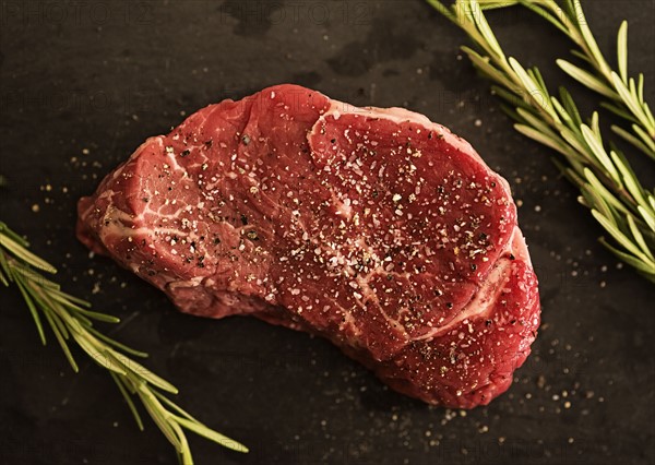 Steak between rosemary on tablecloth