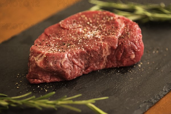 Steak between rosemary on tablecloth