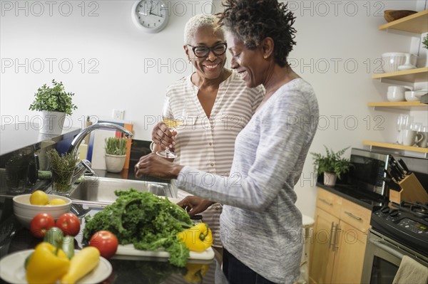 Two women cooking in domestic kitchen.