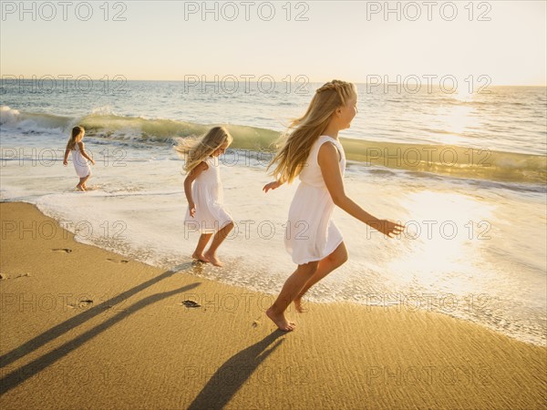 Girls (4-5, 6-7, 8-9) running on beach