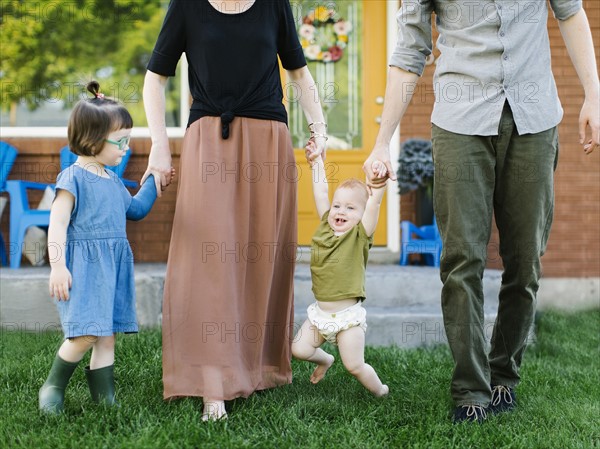 Parents with daughters (2-3, 12-17 months) standing on grass