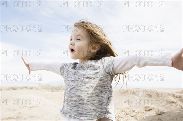 Portrait of little girl (4-5) with outstretched arms and open mouth in field