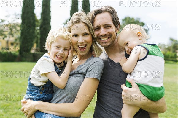 Portrait of parents with sons (12-17 months, 4-5) in park