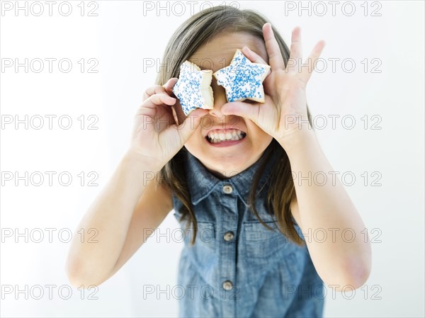 Portrait of girl (6-7) holding cookies in front of eyes