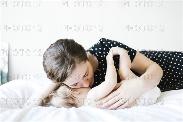 Baby girl (6-11 Months) being hugged by mother