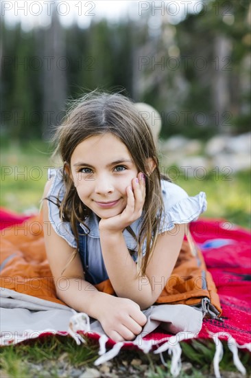 Portrait of girl (8-9) lying on blanket in forest