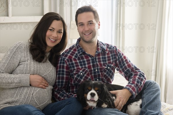 Mid adult couple sitting on sofa with puppy