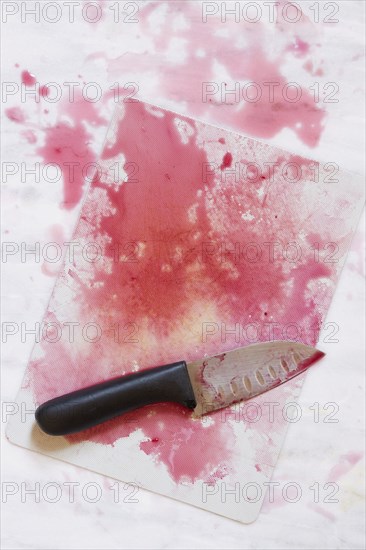 Kitchen knife on chopping board with red juice