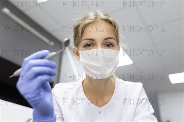 Patient point of view of dental assistant holding dental equipment