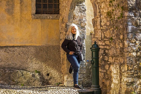 Mature woman leaning on stone arch in Lake Como, Italy