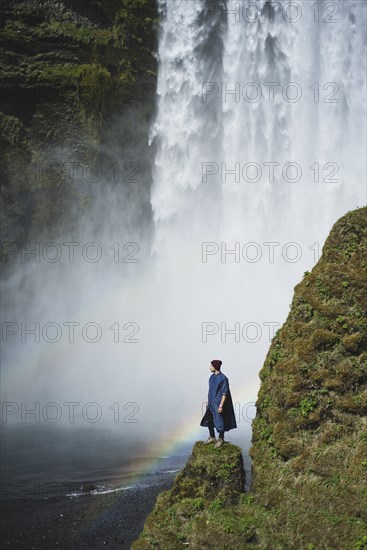 Man standing by Skogafoss waterfall in Iceland