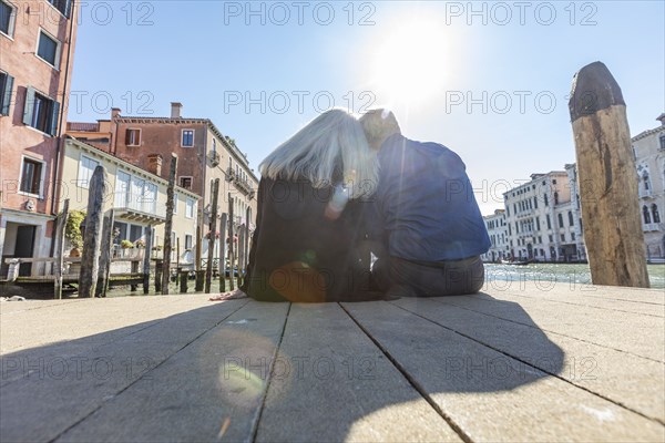 Couple sitting on jetty on Grand Canal in Venice, Italy