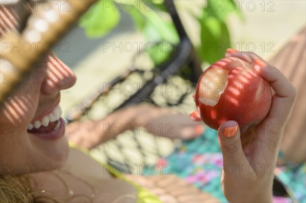 Smiling young woman holding bitten apple