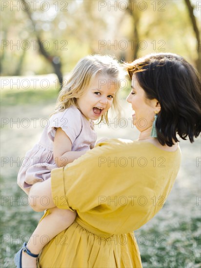 Mother holding her daughter in park