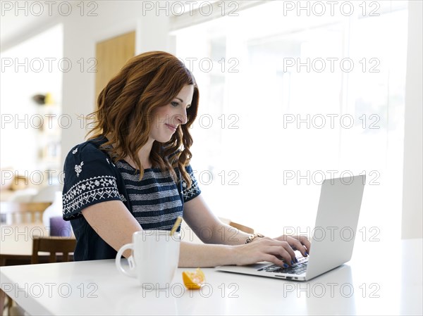 Woman using laptop at dining table