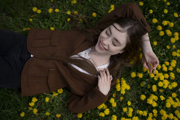 Smiling young woman lying on yellow flowers