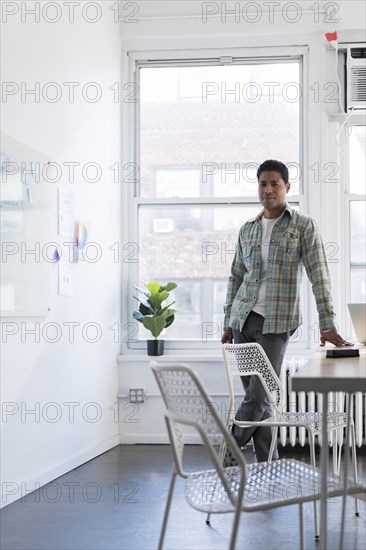 Businessman leaning on desk by whiteboard