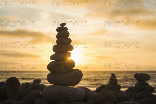 Stacked stones on beach at sunset