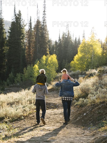 Two fathers piggybacking daughters while hiking