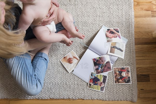 Photographs and book by mother and daughter sitting on rug