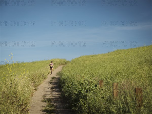 Woman jogging on path through field