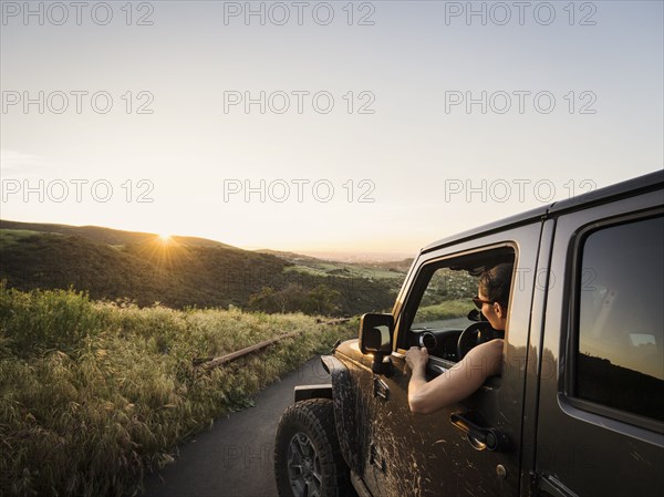 Woman in off road vehicle looking at sunset