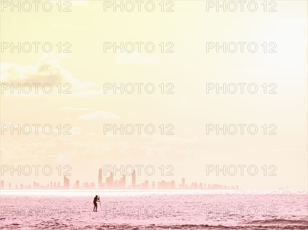 Silhouette of man paddleboarding on sea at sunset