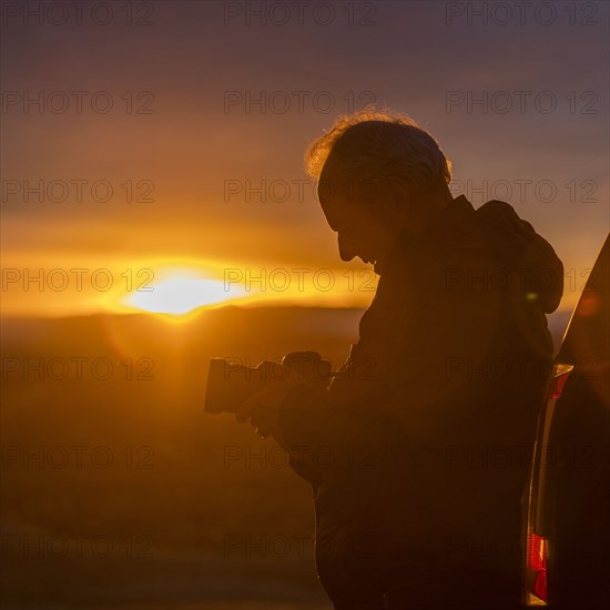 Senior man with camera at sunset