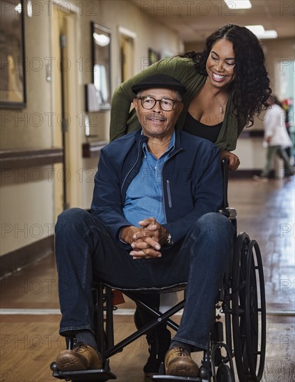 Smiling woman pushing senior man in wheelchair