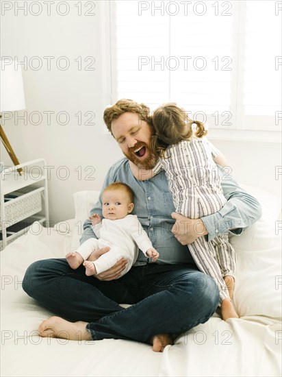 Father sitting on bed with children (2-3 months, 2-3)