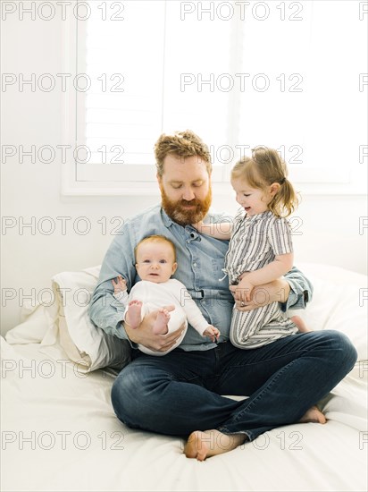 Father sitting on bed with children (2-3 months, 2-3)