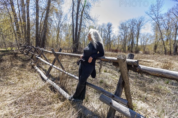 USA, Idaho, Bellevue, Senior woman relaxing on rustic rail fence