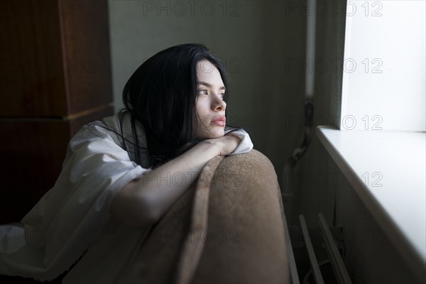 Young woman looking through window