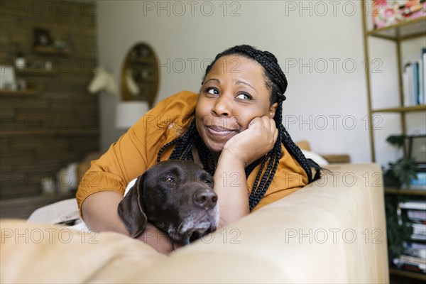 Woman lying on sofa with her dog