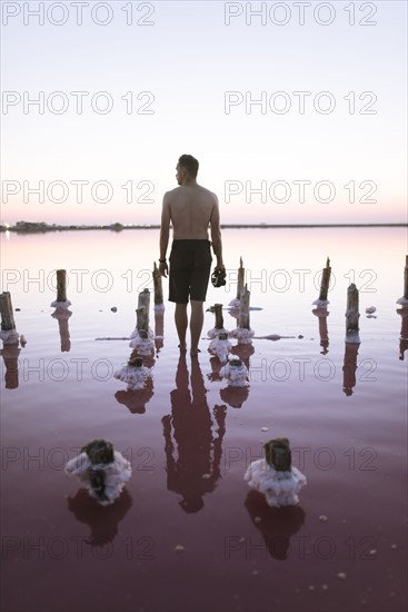 Ukraine, Crimea, Man standing in salt lake and holding camera