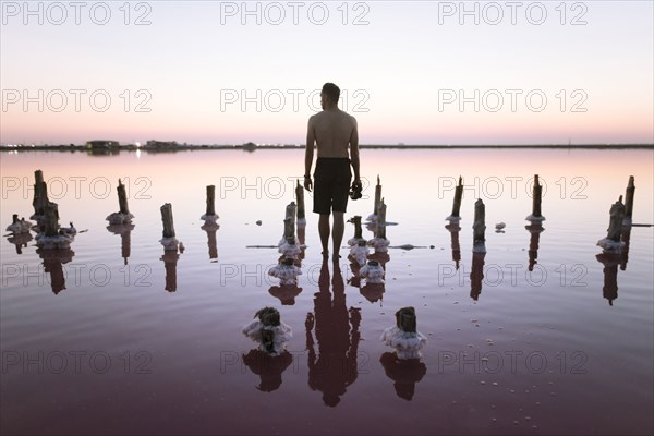 Ukraine, Crimea, Man standing in salt lake and holding camera