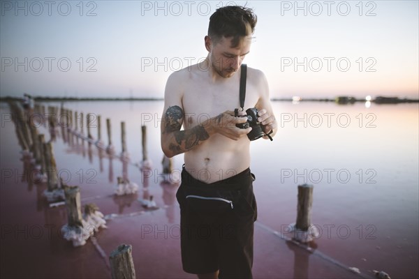 Ukraine, Crimea, Man standing in salt lake and holding camera